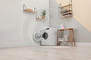 Modern washing machine in room interior