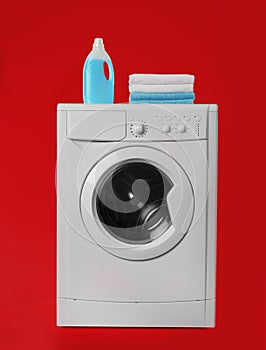 Modern washing machine with stack of towels and detergent on background. Laundry day