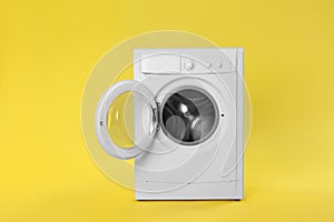 Modern washing machine on yellow background. Laundry day