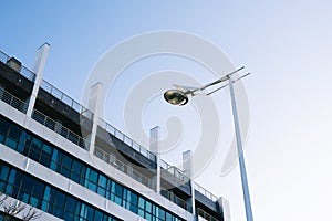 Modern white building with bluish glass and a white lamppost with blue sky on sunny day