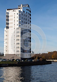 A modern white building near the river against a blue sky