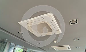 Modern white ceiling mounted cassette type air conditioner in office building system work. Ventilation compressor