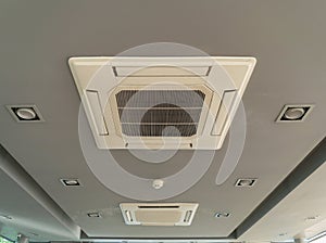 Modern white ceiling mounted cassette type air conditioner in office building system work. Ventilation compressor