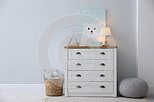 Modern white chest of drawers near light wall in child room, space for text. Interior design