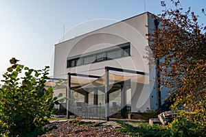 Modern, white, cube, elegant, minimalist style passive house with large panoramic windows, grey shutters in maintained garden in