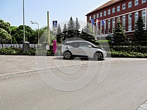 Modern white electric car charging on the street in Kosice, Slovakia. Summer cityscape with a car on an uncluttered clean street,