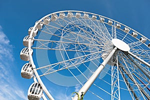 Modern white ferris wheel against blue sky