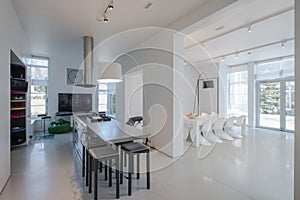 Modern white interior of spacious private house. Kitchen dinner room.