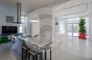 Modern white interior of spacious private house. Kitchen dinner room.