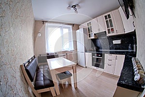 Modern white kitchen with black countertop, sink, cupboards and window fisheye photo