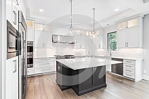 A modern white kitchen with a large grey island.