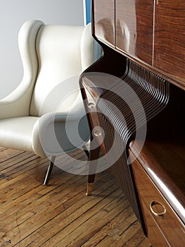 Modern white leather chair and wooden sideboard.