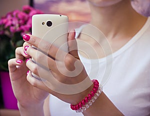 Modern white mobile phone with a camera in female hands with pur