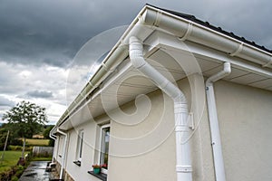 White plastic rain gutter system with drainage pipe