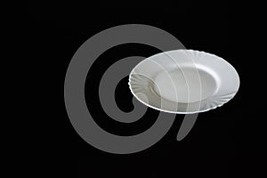 Modern white plate isolated on black background.