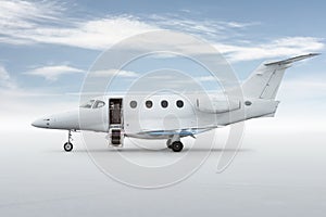 Modern white private jet with an opened gangway door isolated on bright background with sky