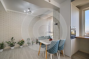 A modern white studio apartment with a dining table and row of green plants