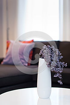 Modern white vase with violet flower in living room