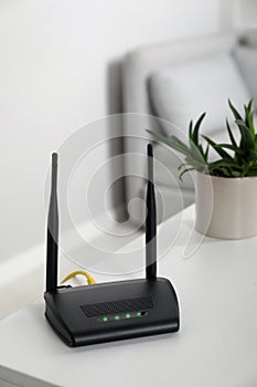 Modern Wi-Fi router on white table in room