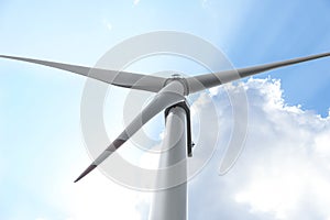 Modern wind turbine against blue sky, low angle view. Energy efficiency