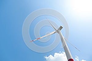 Modern wind turbine against blue sky, low angle view. Energy efficiency