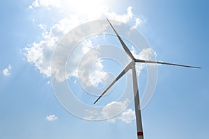 Modern wind turbine against blue sky, low angle view. Energy efficiency