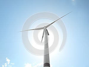 Modern wind turbine against blue sky, low angle view. Energy efficiency