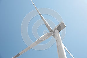 Modern wind turbine against blue sky, low angle view. Energy efficiency