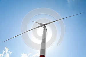 Modern wind turbine against blue sky, low angle view. Energy efficiency