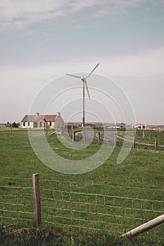 Modern wind turbine next to a residential Building at the countryside of Kirkwall, Scotland, vertical shot