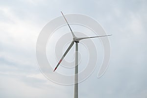 Modern wind turbine renewable energy during daylight with cloudy sky, view from low angle