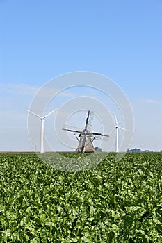 Modern wind turbines behind an old traditional windmill
