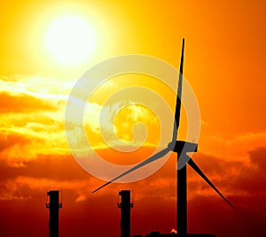 Modern windmill and chimneys of power station at sunrise