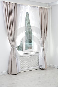Modern window with curtains in room.