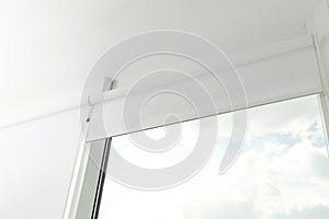 Modern window with white roller blinds, low angle view
