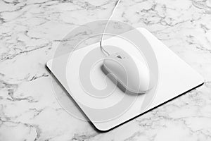 Modern wired optical mouse and pad on marble table