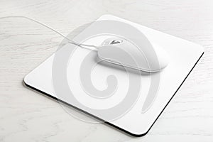 Modern wired optical mouse and pad on wooden table