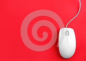 Modern wired optical mouse on red background. Space for text