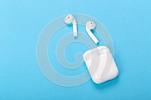 Modern wireless bluetooth earphones with charging case on a blue background. The concept of modern technology