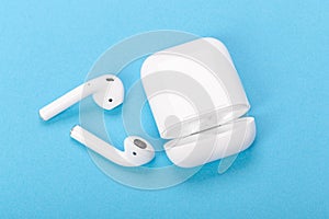 Modern wireless bluetooth earphones with charging case on a blue background. The concept of modern technology