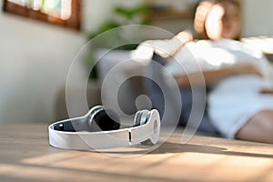 Modern wireless headphones is on the table over blurred background of pregnant woman