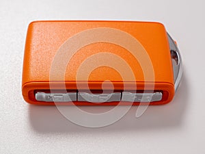 Modern wireless orange car ignition key on a white background.