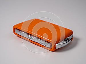 Modern wireless orange car ignition key on a white background.