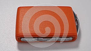 Modern wireless orange car ignition key on a white background.