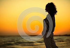 Modern woman on beach in evening looking into distance