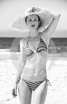 Modern woman in beachwear and straw hat on the seashore