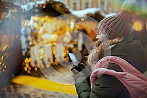 modern woman at christmas fair in city using smartphone