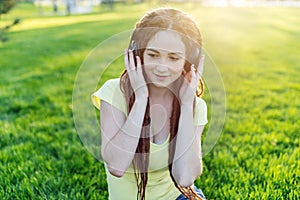 Modern woman with dreadlocks listening to music with her headphones in autumn Sunny Park. Concept of good mood