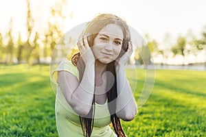 Modern woman with dreadlocks listening to music with her headphones in autumn Sunny Park. Concept of good mood