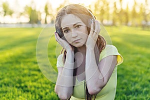 Modern woman with dreadlocks listening to music with her headphones in autumn Sunny Park. Concept of good mood